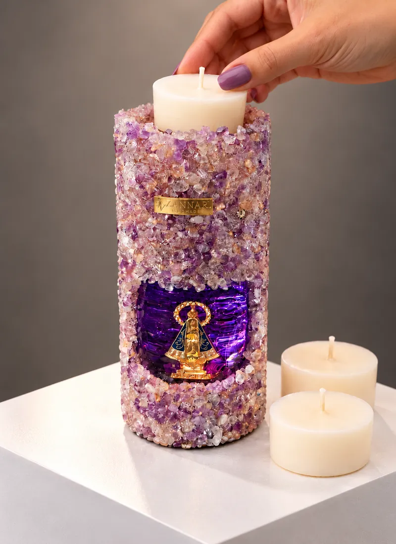 Mão trocando o refil de uma vela gruta de ametista com a imagem de Nossa Senhora iluminada